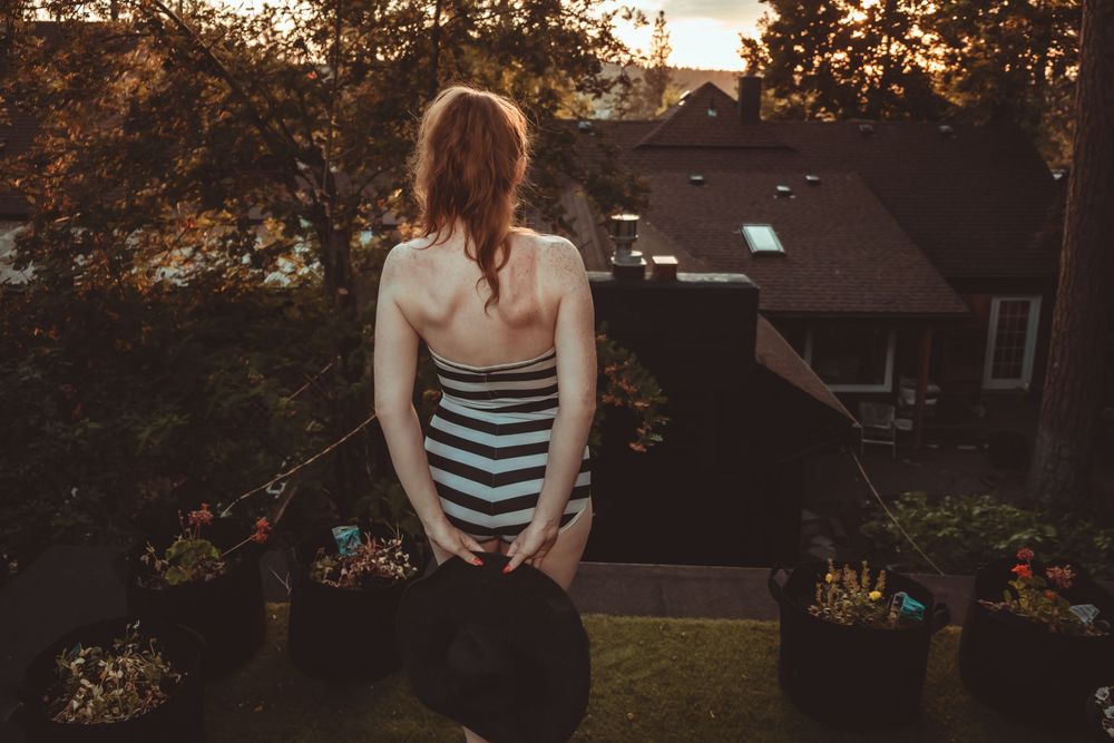 Back view of striped swimsuit against sunset with rooftop garden setting.