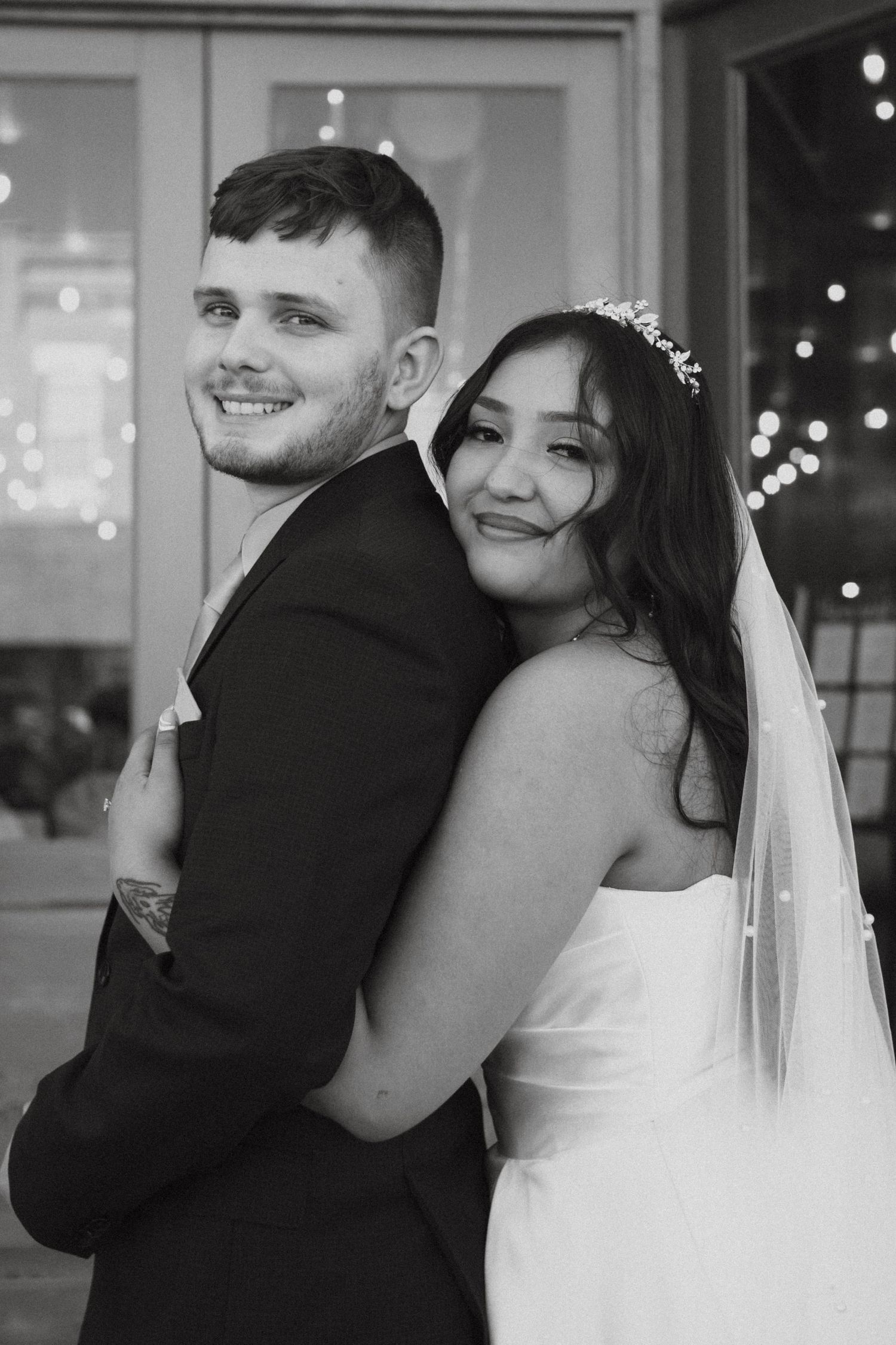 Black and white portrait of a happy bride and groom embracing and smiling at their wedding celebration.
