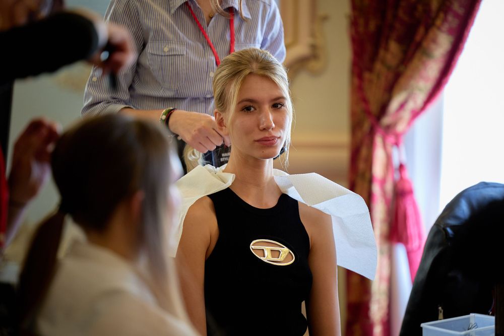 Behind the scenes at a fashion show with makeup artists preparing models.