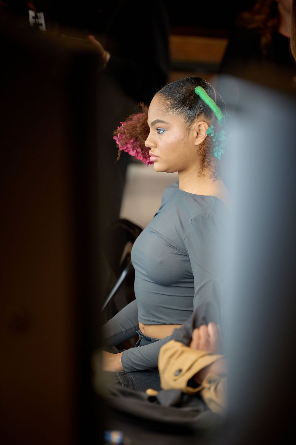 Behind the scenes photo shows a performer in a gray crop top getting ready in a makeup chair.