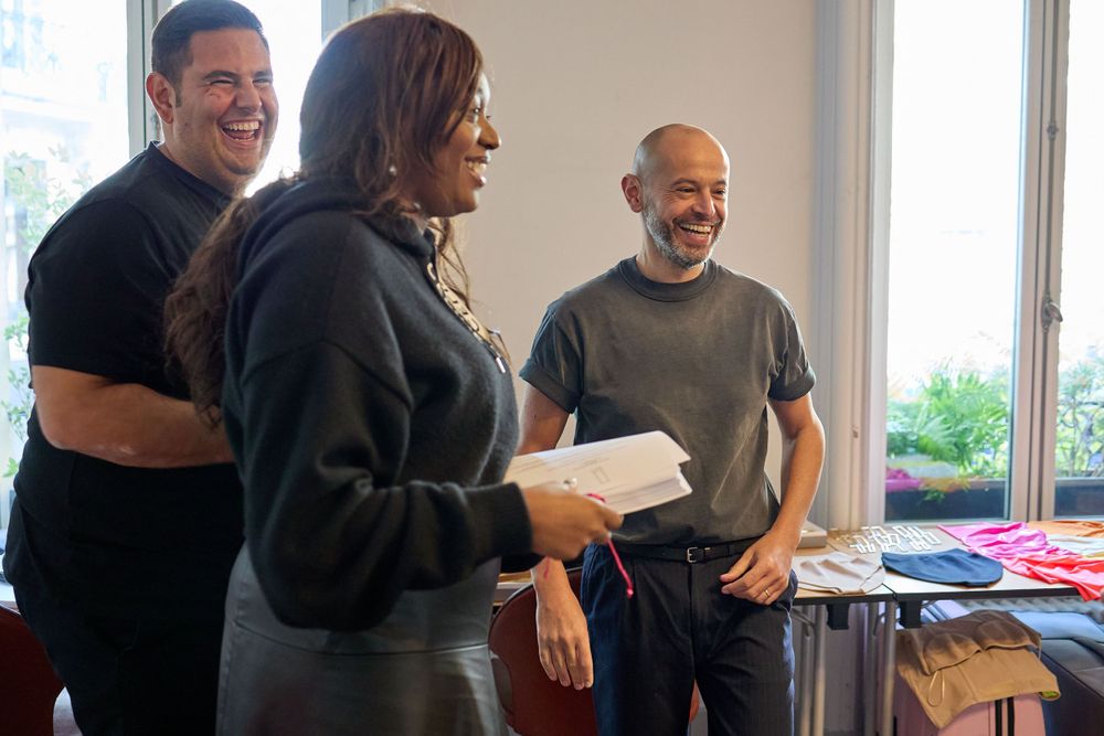 Creative team members review fashion designs in bright studio setting.