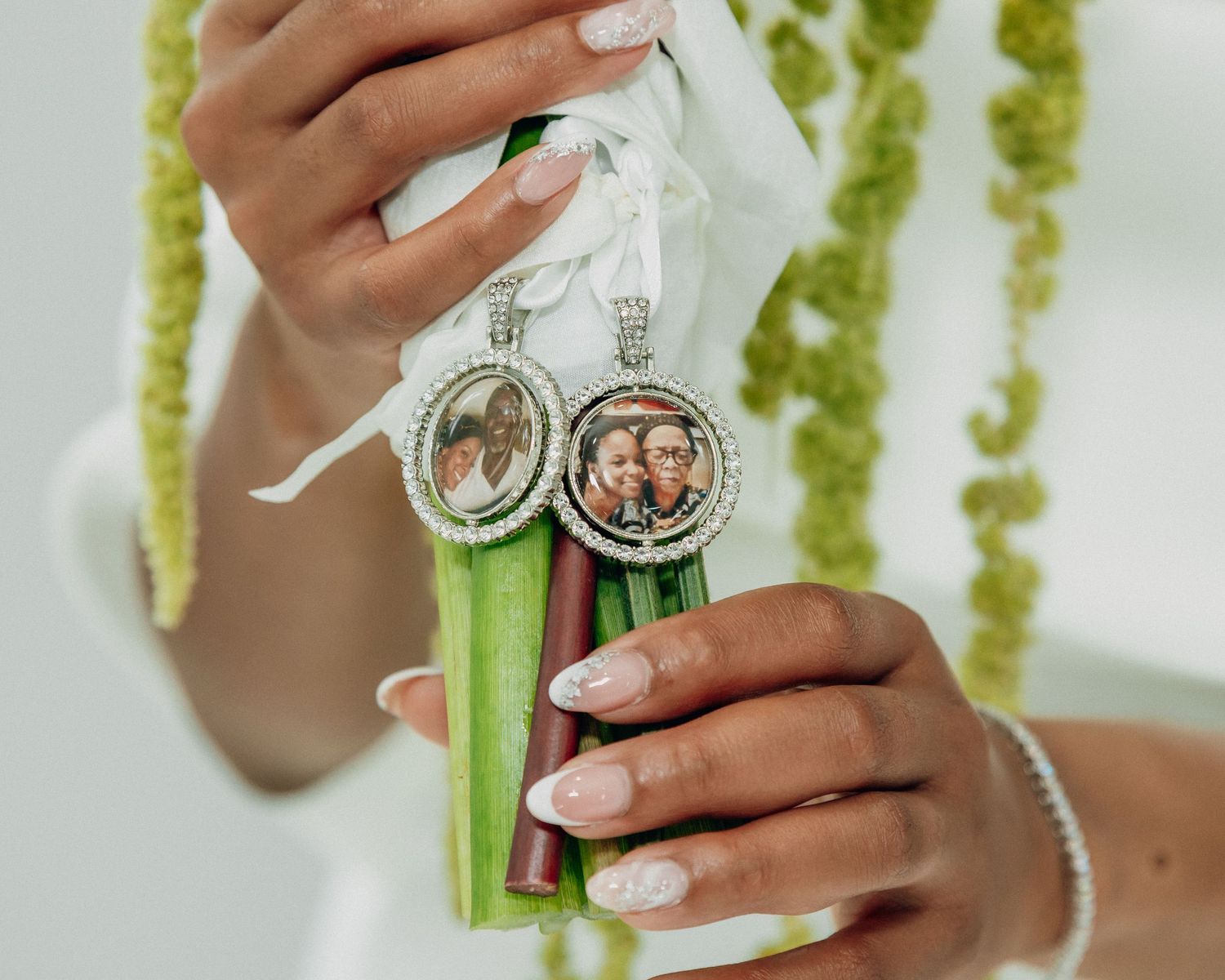 Close-up of hands holding vintage compass ornaments with white ribbons and green stems.
