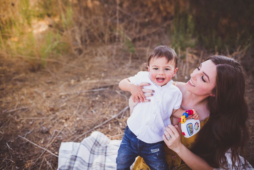 A joyful moment shared between parent and child outdoors in a sunlit natural setting.