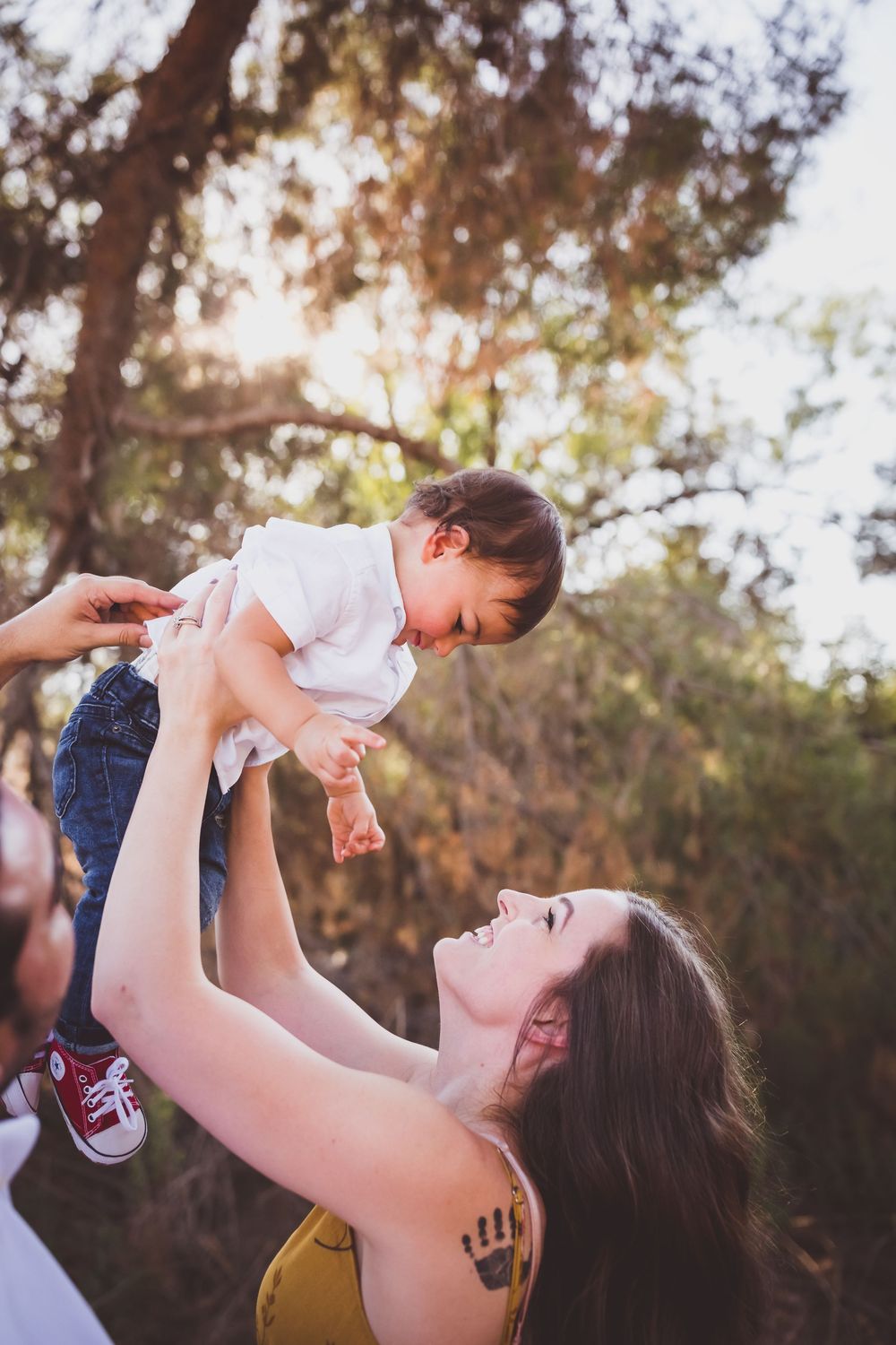 A tender outdoor moment between parent and child as they play together in dappled sunlight.