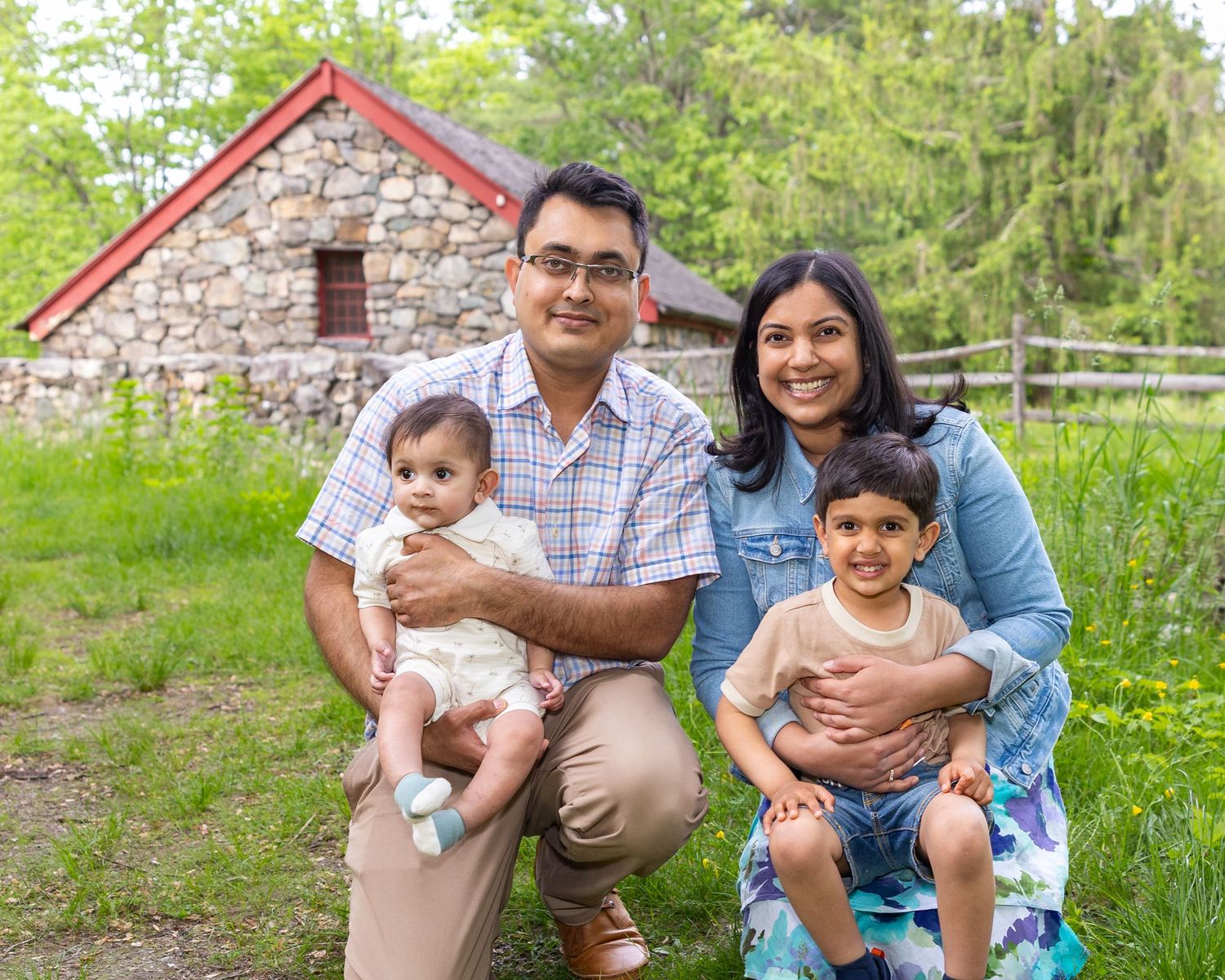 A happy family enjoying a spring day together outdoors near a rustic stone wall.