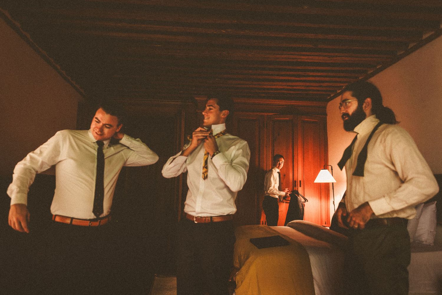 Three groomsmen in white shirts performing and having fun at an indoor reception.