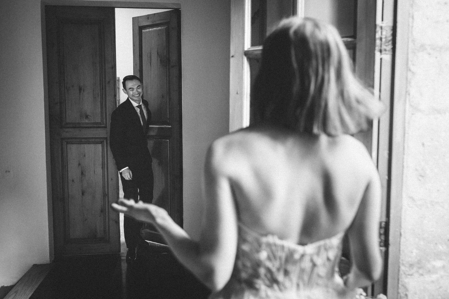 Black and white image showing couple's first look moment through doorway.