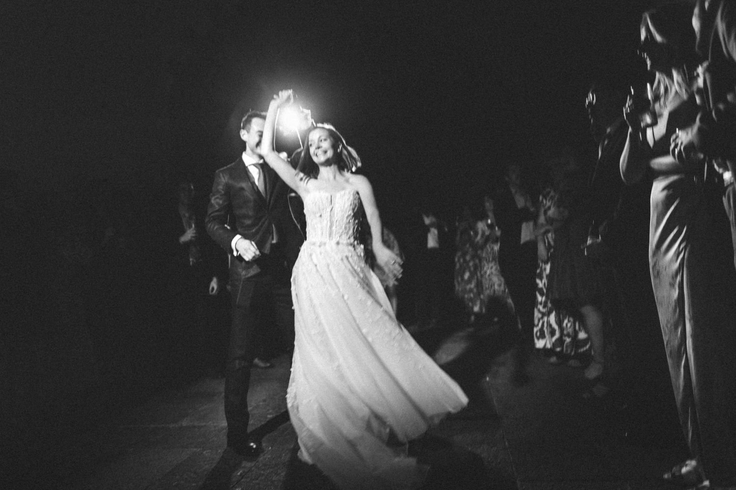 Couples dancing together at an evening wedding reception under dramatic lighting.