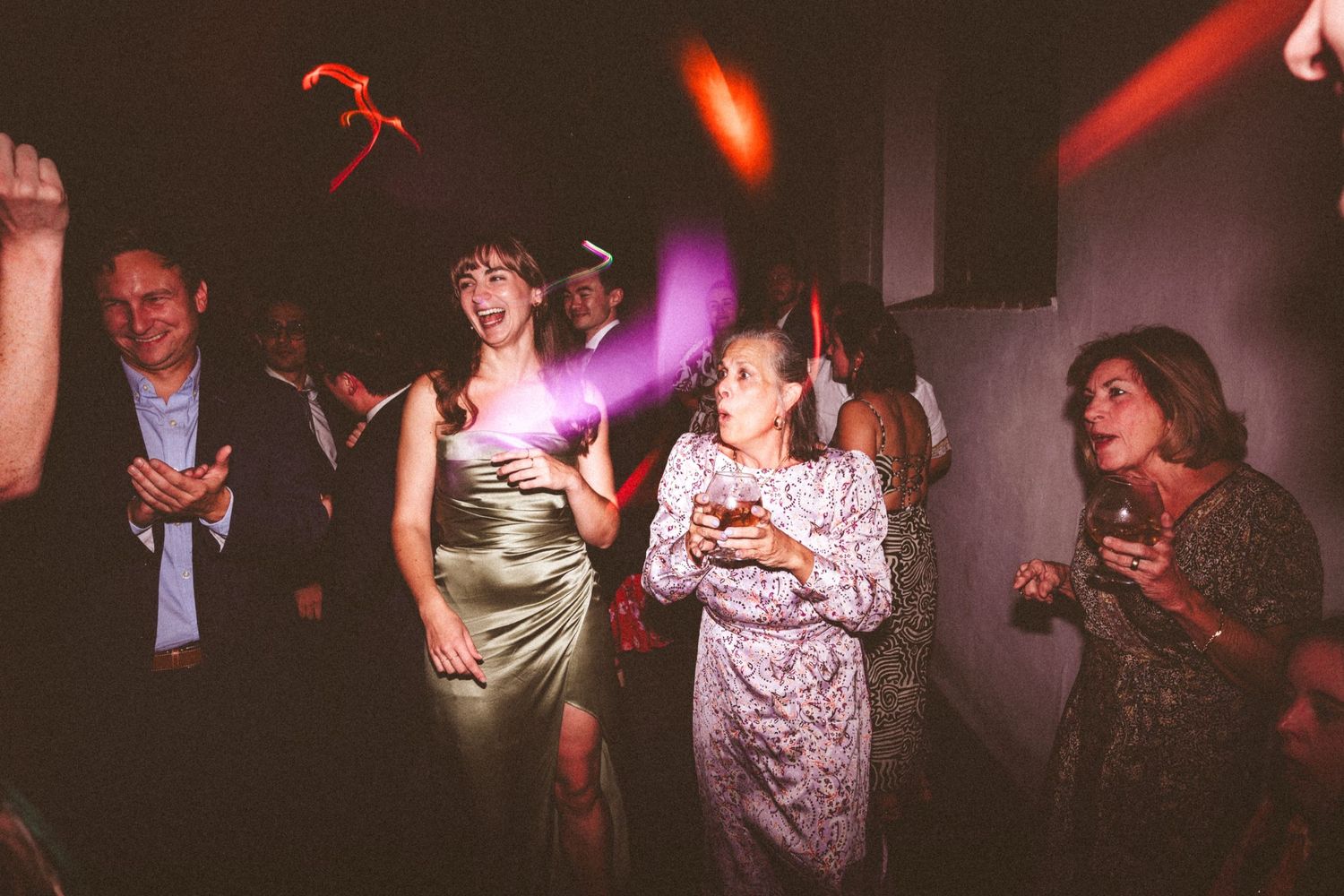 Wedding reception guests dancing under dramatic red lighting in a dark venue.