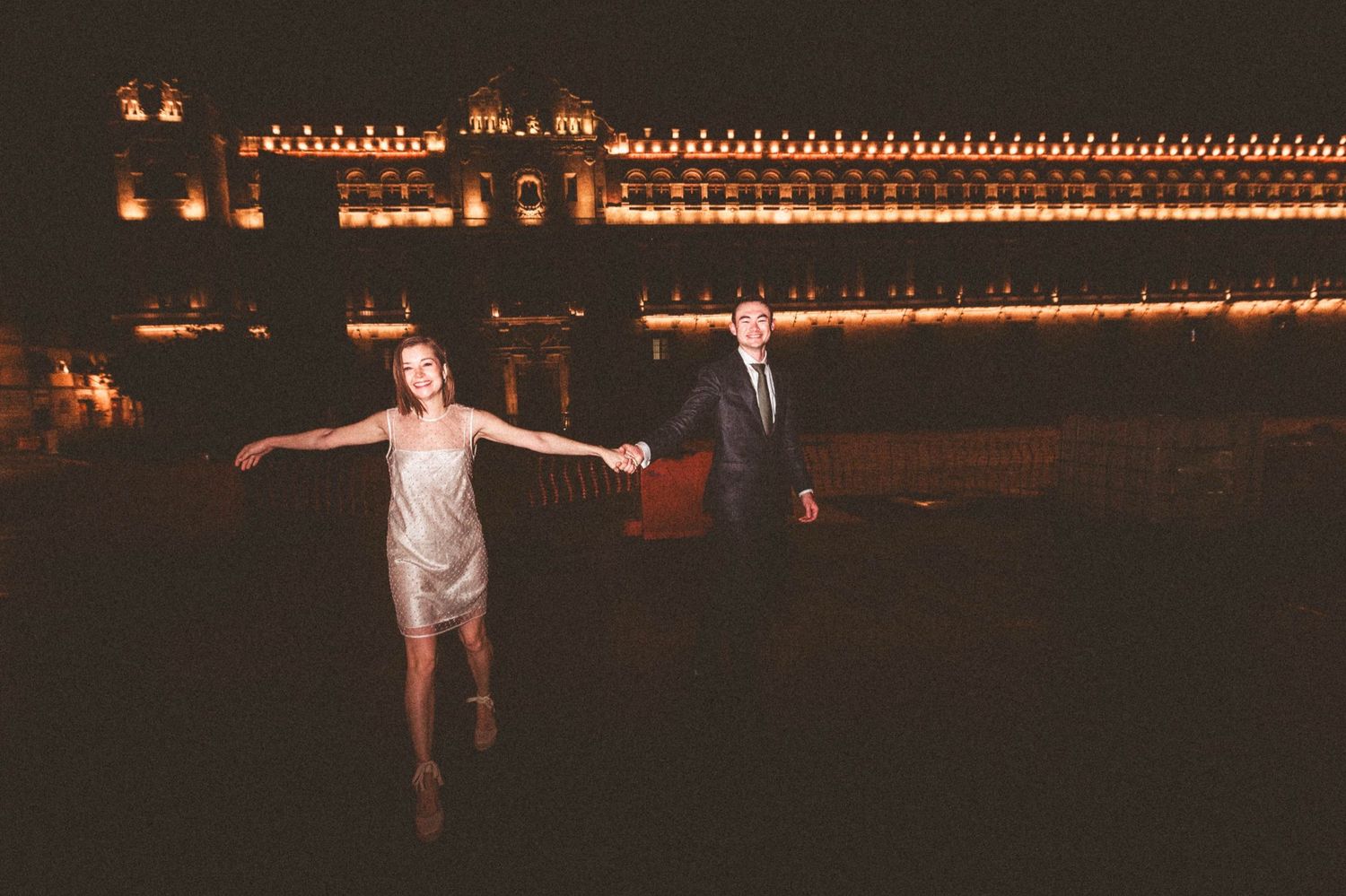 People posing against a backdrop of decorative string lights at night.