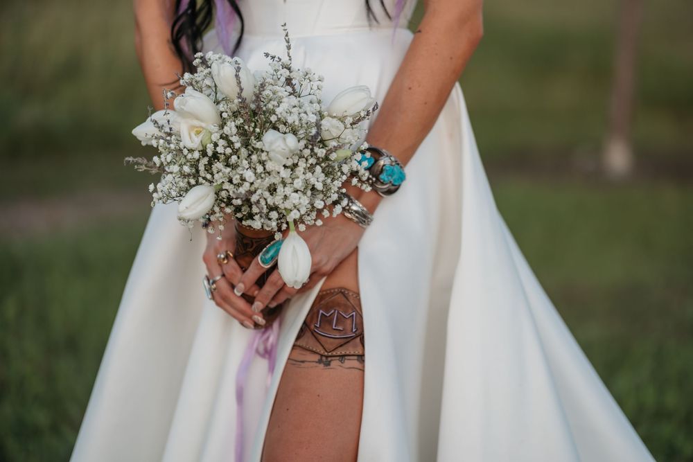 Close-up of wedding bouquet with white flowers and baby's breath held by hands with turquoise jewelry.