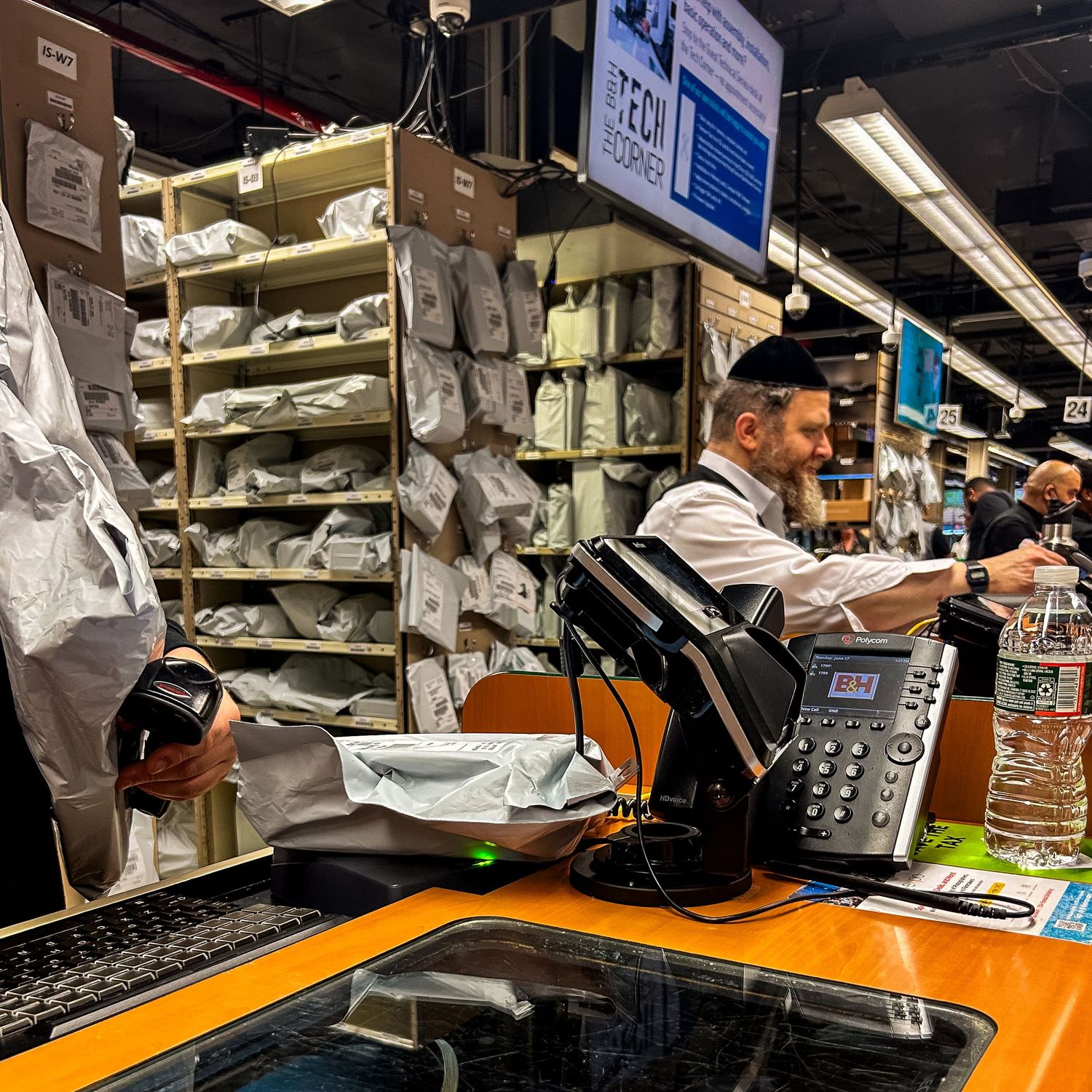 A workspace in a retail store with phone equipment and shelves of products stacked behind an orange counter surface.