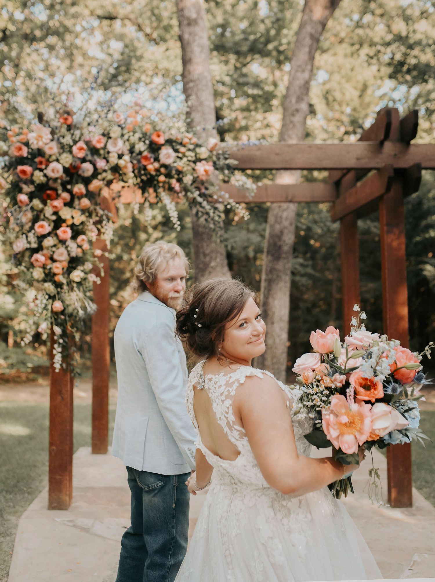 Close-up of bride and groom under the floral arbor, surrounded by soft pinks and pastels
