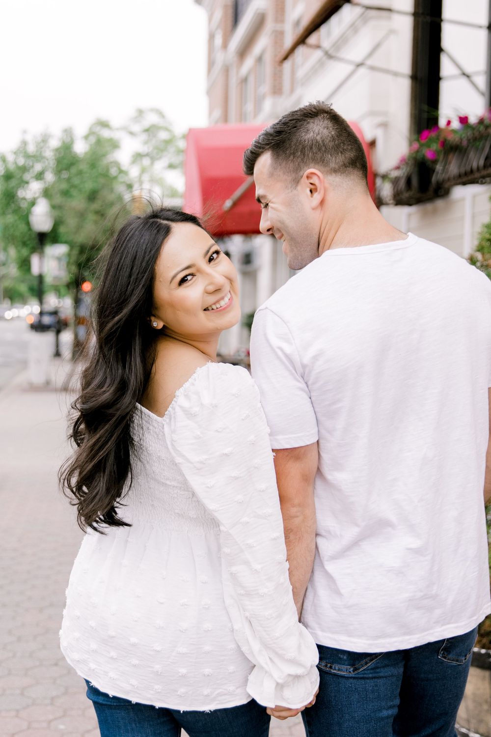 Mariela and Nick walking hand-in-hand down a tree-lined street in Cranford, New Jersey.