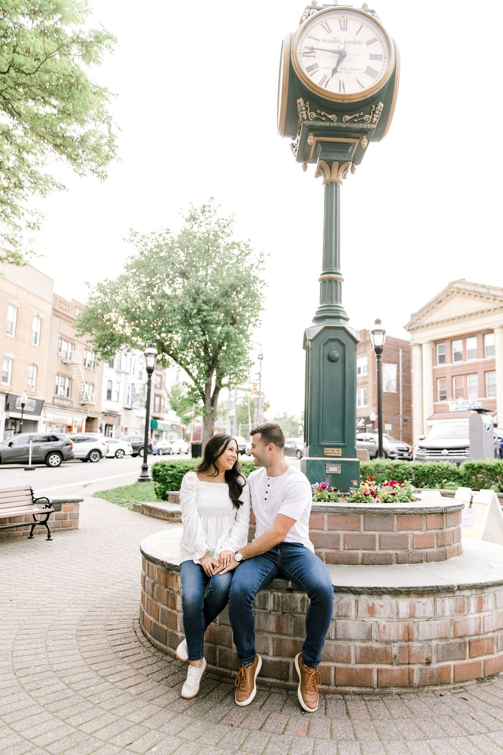 Couple cuddling on a bench in downtown Cranford during their engagement session.