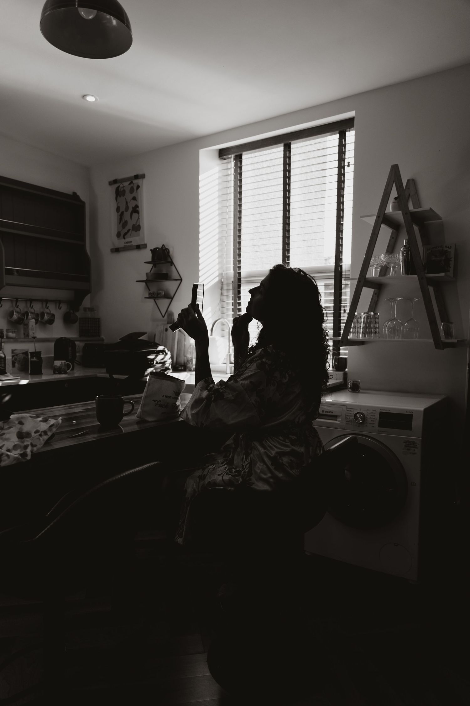 Silhouetted figure working at a desk in a moody interior space with sunlight streaming through venetian blinds.