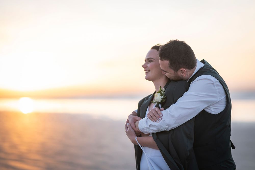Romantic sunset embrace captured in silhouette against ocean backdrop.