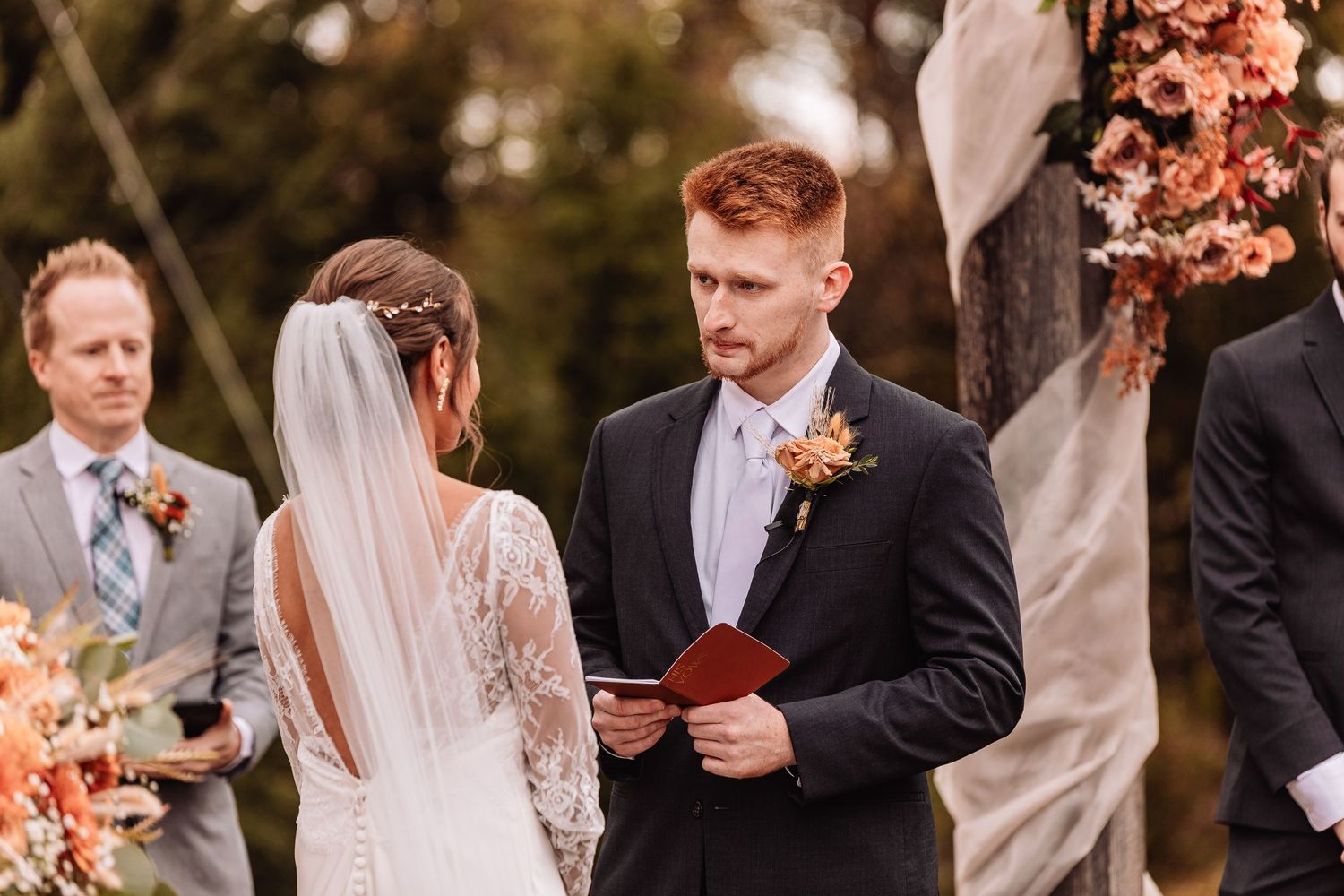 Wedding party celebrates outdoors during autumn with warm sunset lighting and fall-colored floral arrangements.