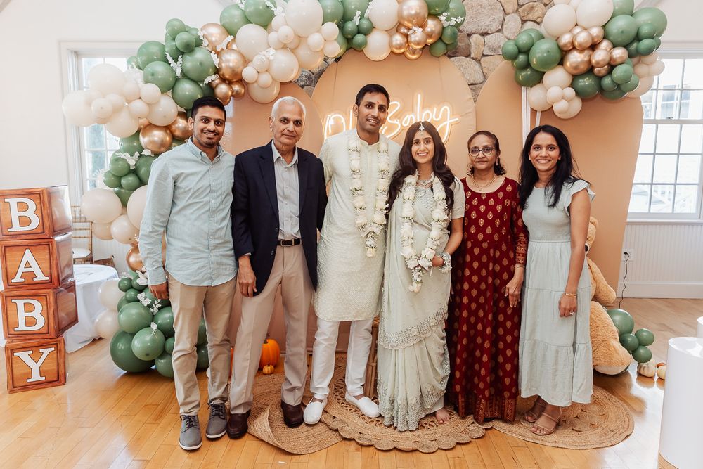Group photo in front of balloon arch with pastel green and peach colors and 'BABY' blocks.