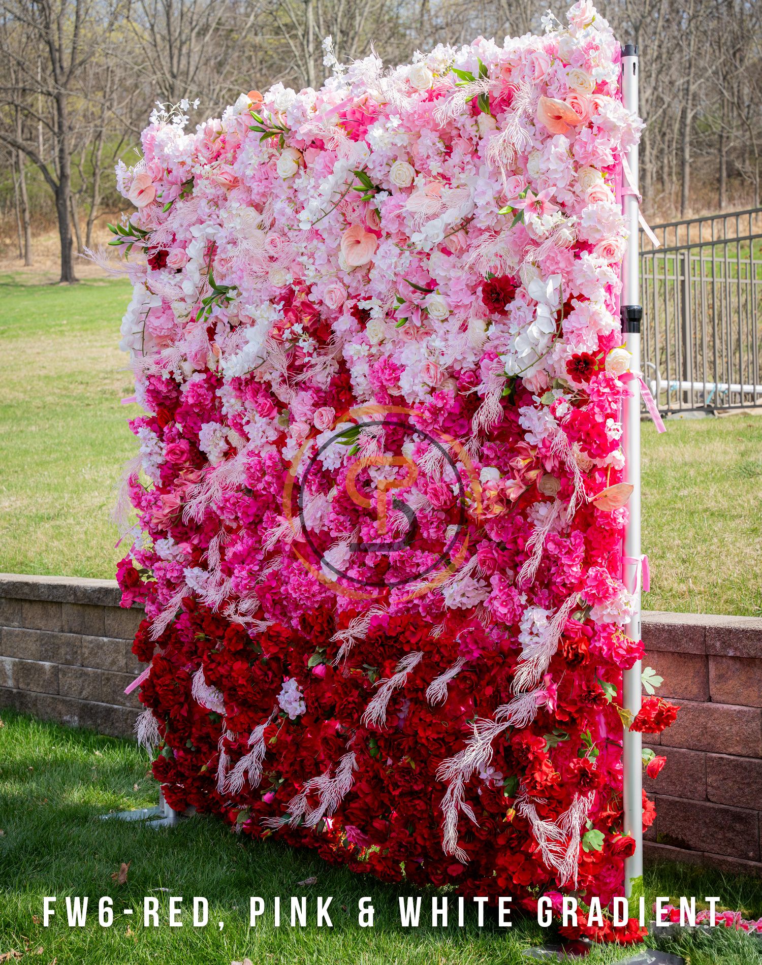 Ombre flower wall transitioning from white to pink to red roses with outdoor backdrop.