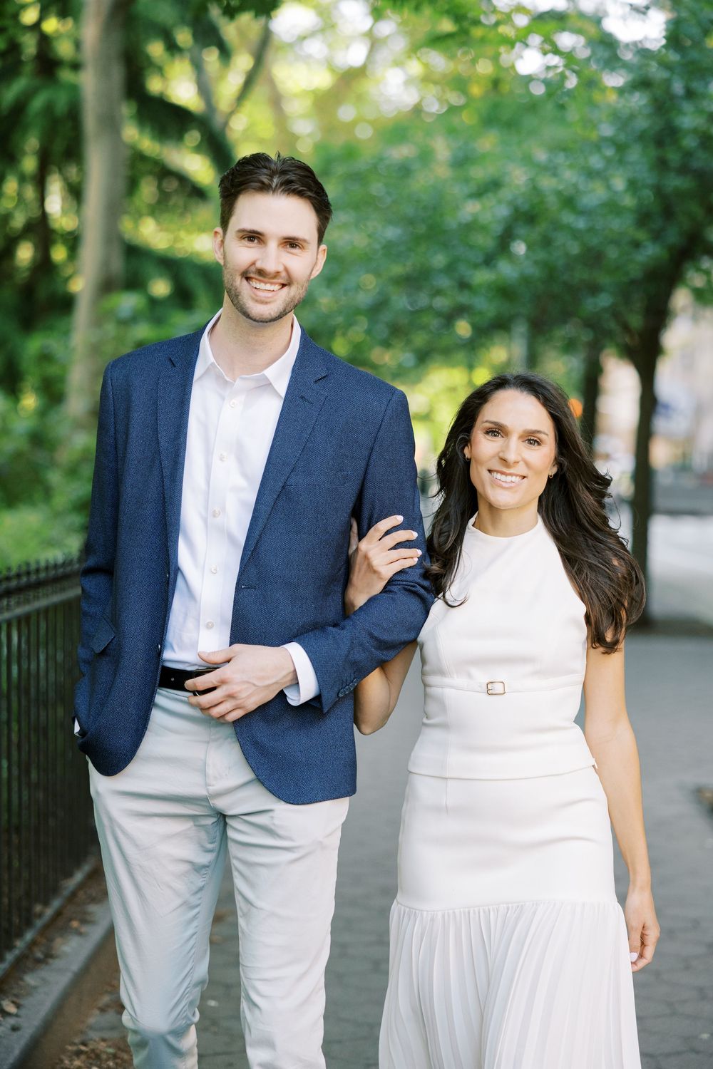 Stylish couple in coordinated navy and white outfits walking along park pathway in New York City.