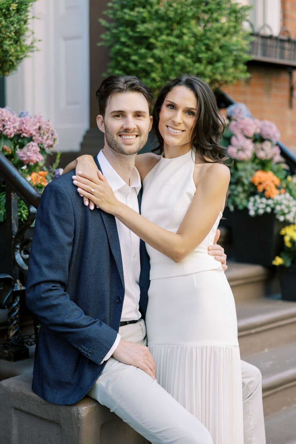 A couple poses together on city steps with colorful flower boxes in the background in New York City.