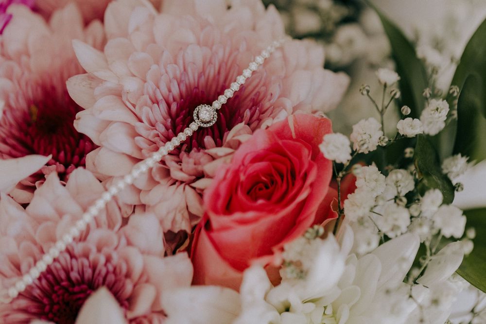 Close-up view of pink and red flowers including roses and chrysanthemums with delicate white baby's breath in a bouquet. Wedding photograph