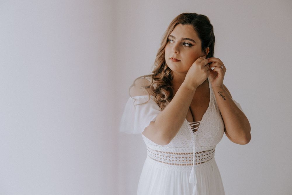 Indoor portrait showing elegant white lace dress and soft window lighting.
