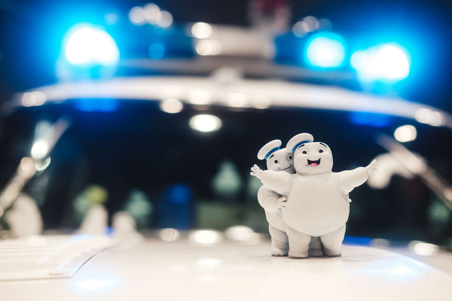 A small white fuzzy toy with blue police lights blurred in the background during nighttime.