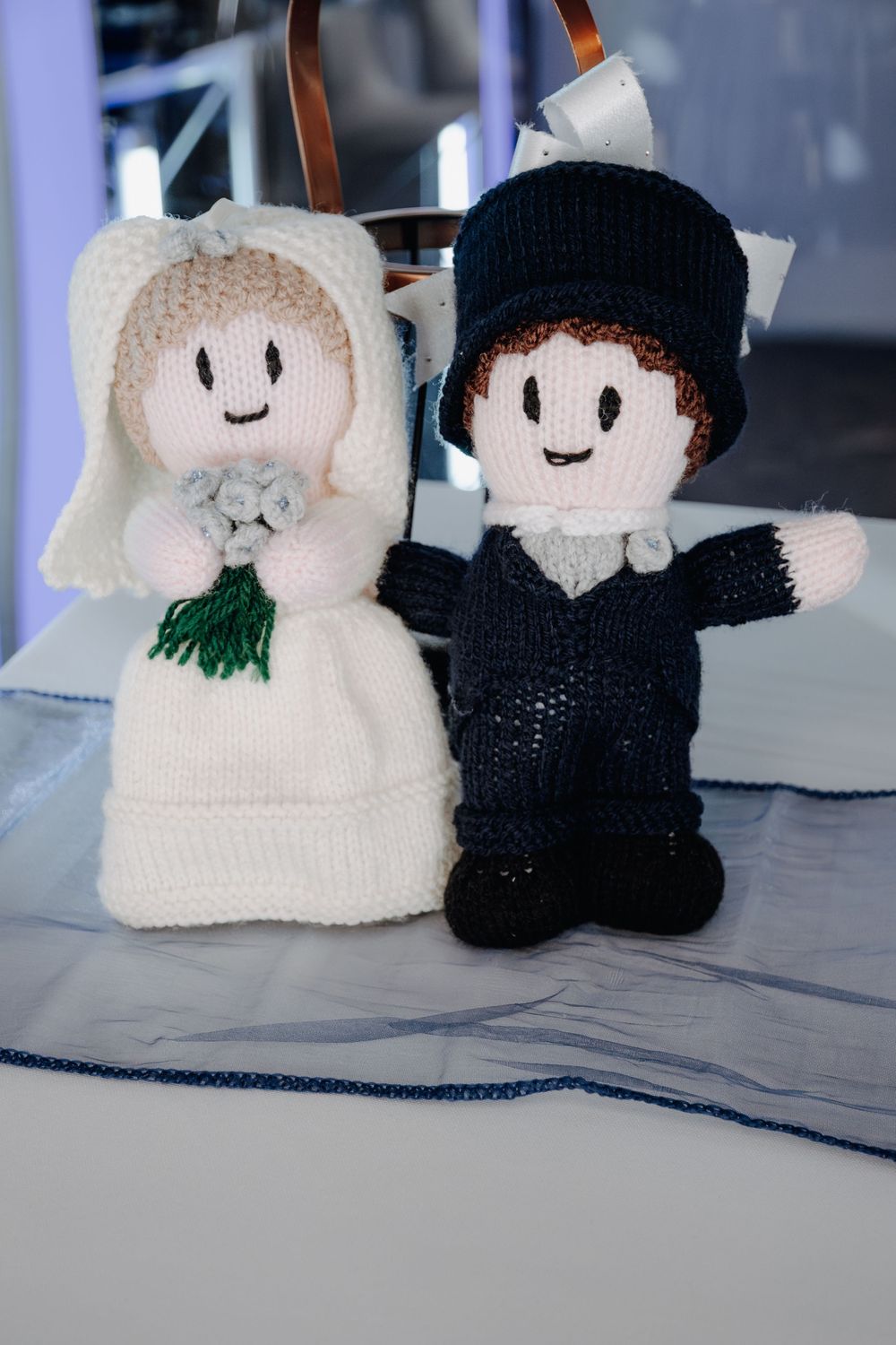 Handmade knitted bride and groom dolls in white dress and black suit displayed as wedding decorations.