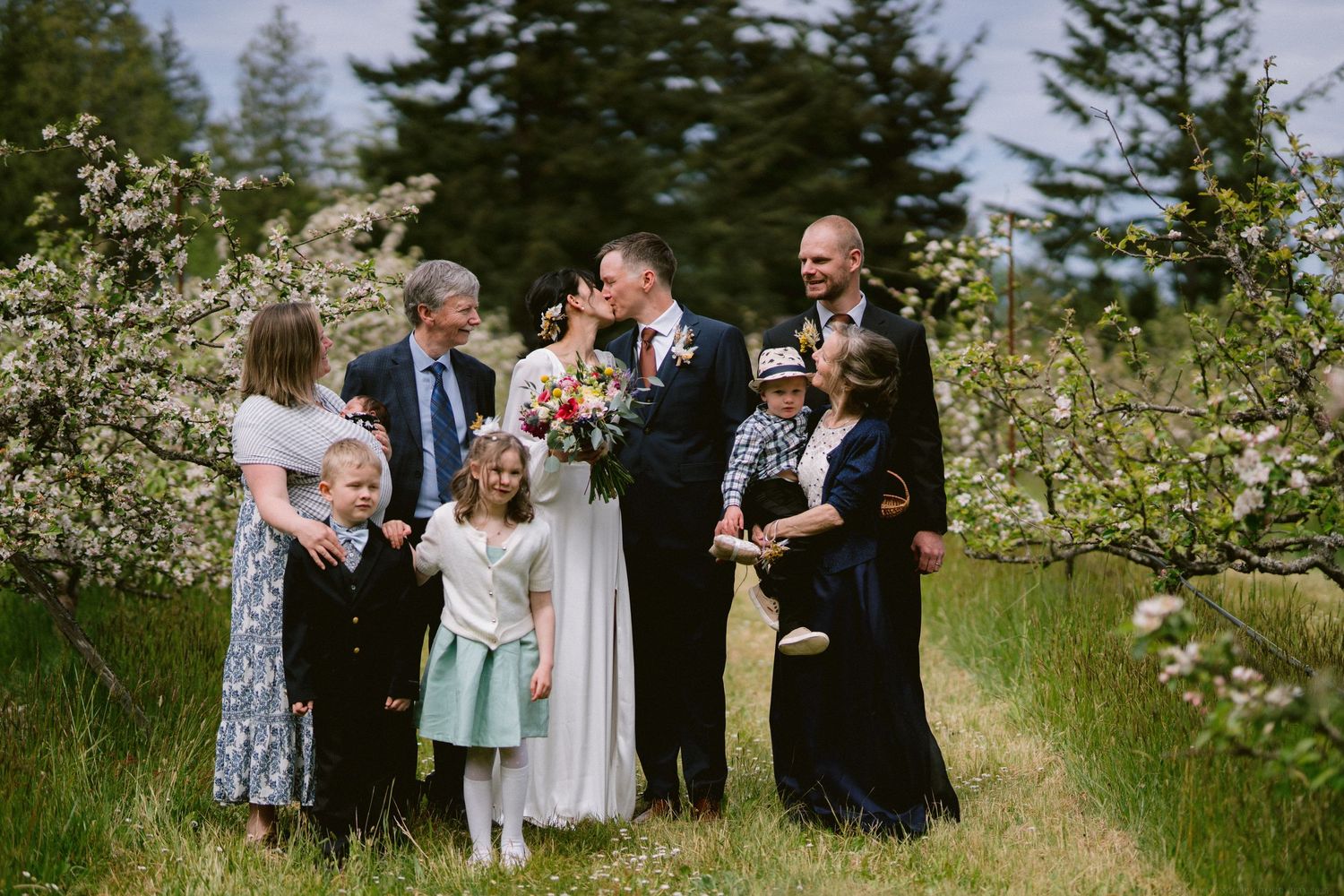 Wedding party posing together in a blooming garden during a sunny outdoor celebration.