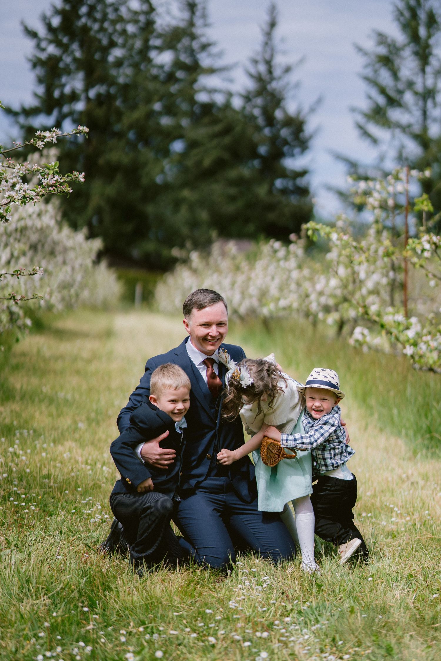 A joyful family moment with children and a dog gathered in a blooming meadow on a sunny day.