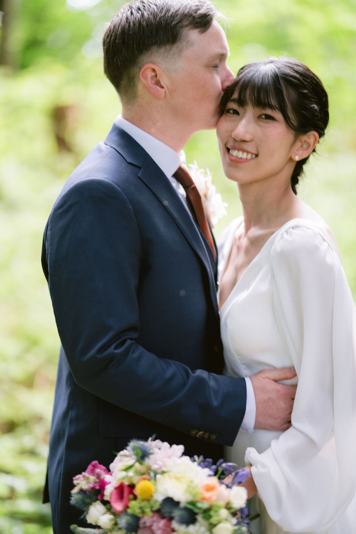 A tender wedding moment captured between newlyweds with soft natural lighting in a garden setting.