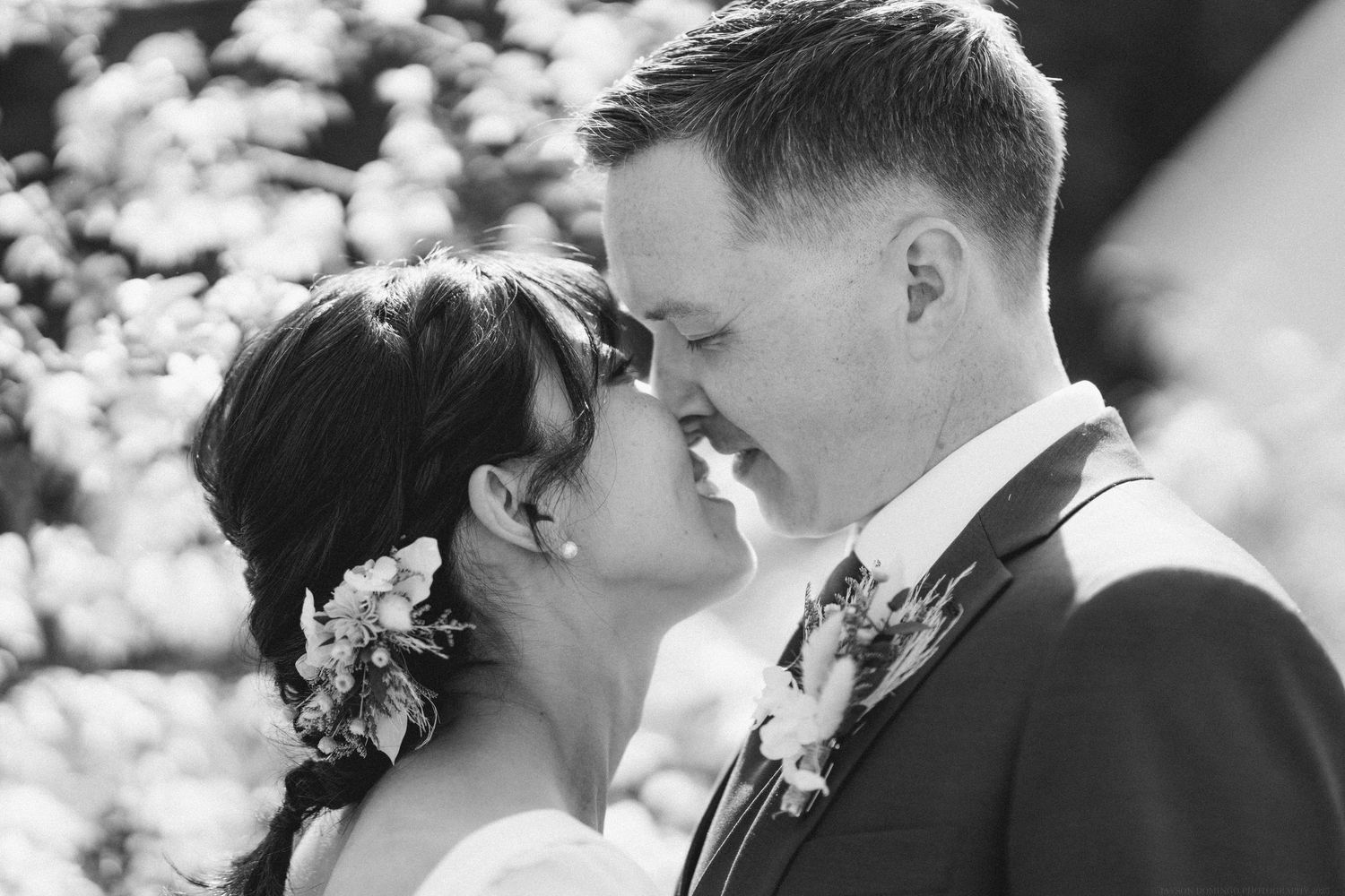 A black and white intimate moment between newlyweds with floral hair accessories.