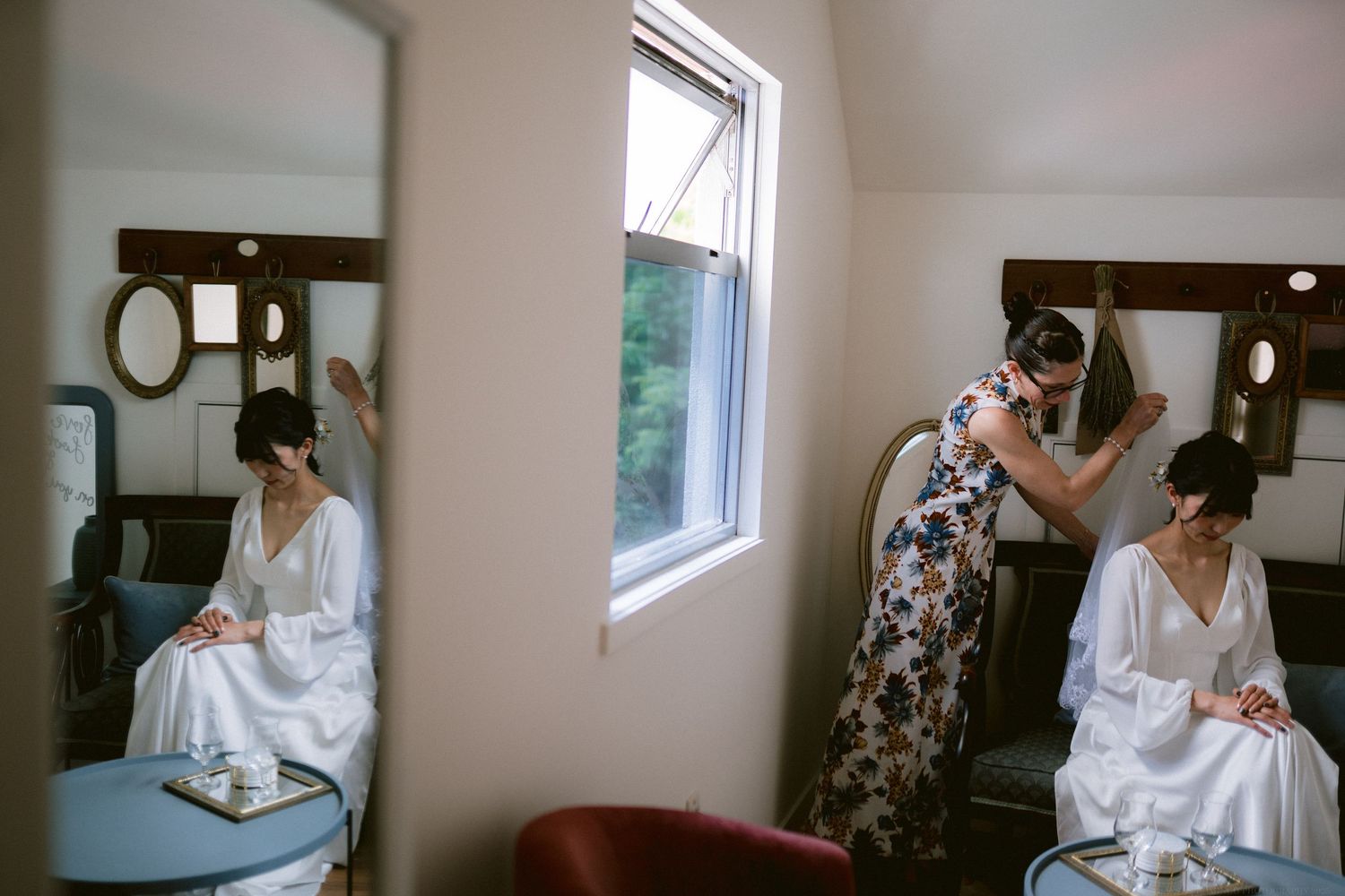 Getting ready scene in a bridal preparation room with mirrors, window light, and white robes.