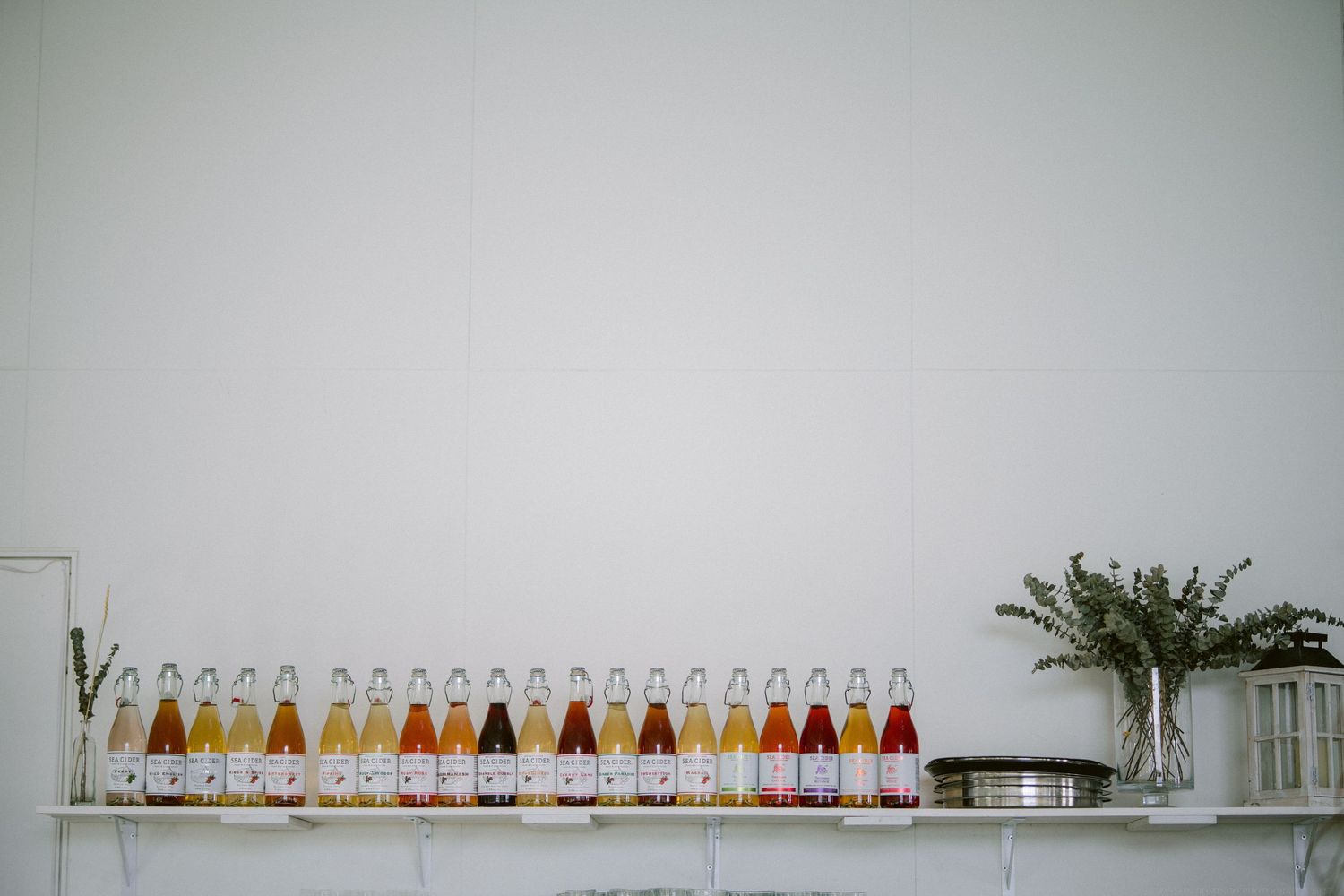 Row of colorful bottled beverages displayed on white shelf with minimal decor.