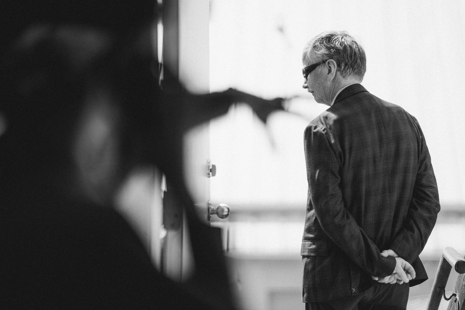 Black and white artistic photo of someone in formal attire captured from behind.