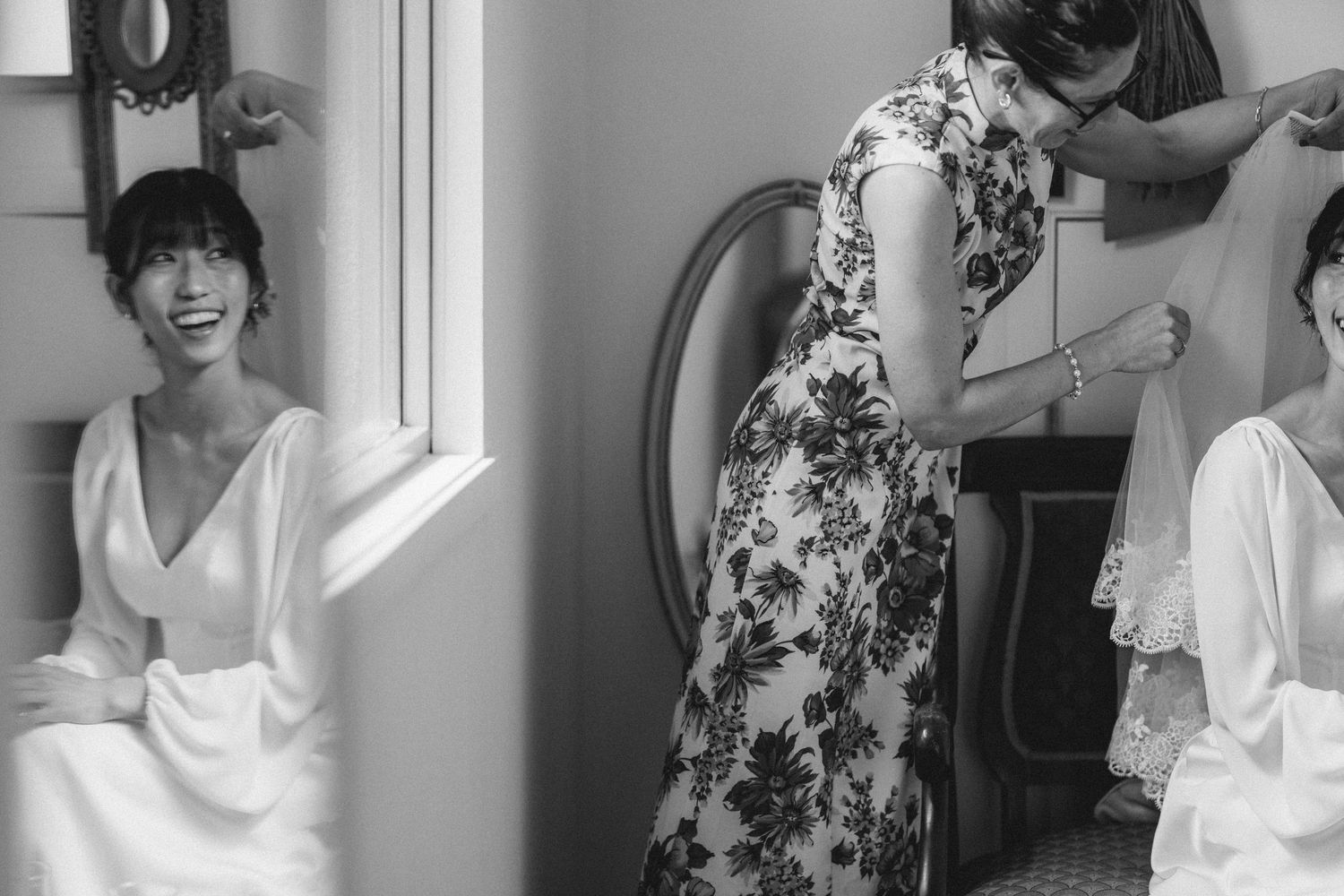 Wedding preparation scene in black and white showing people getting ready by window.