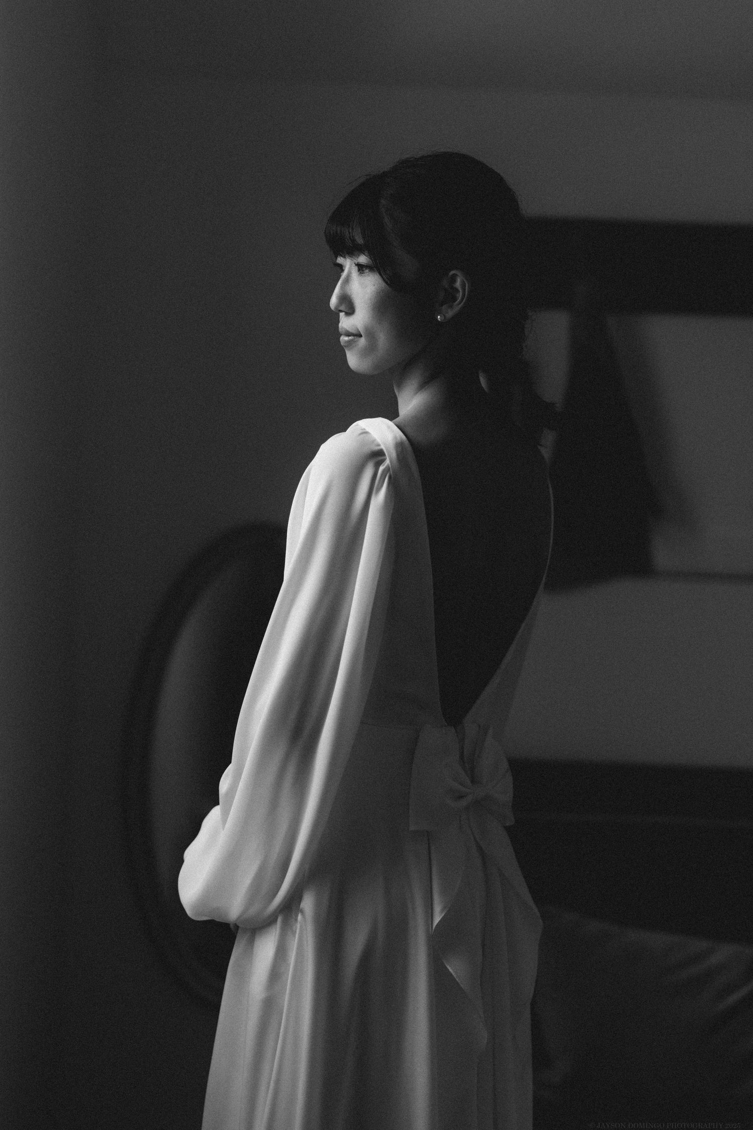 Dramatic black and white portrait of bride in flowing white dress with long sleeves.