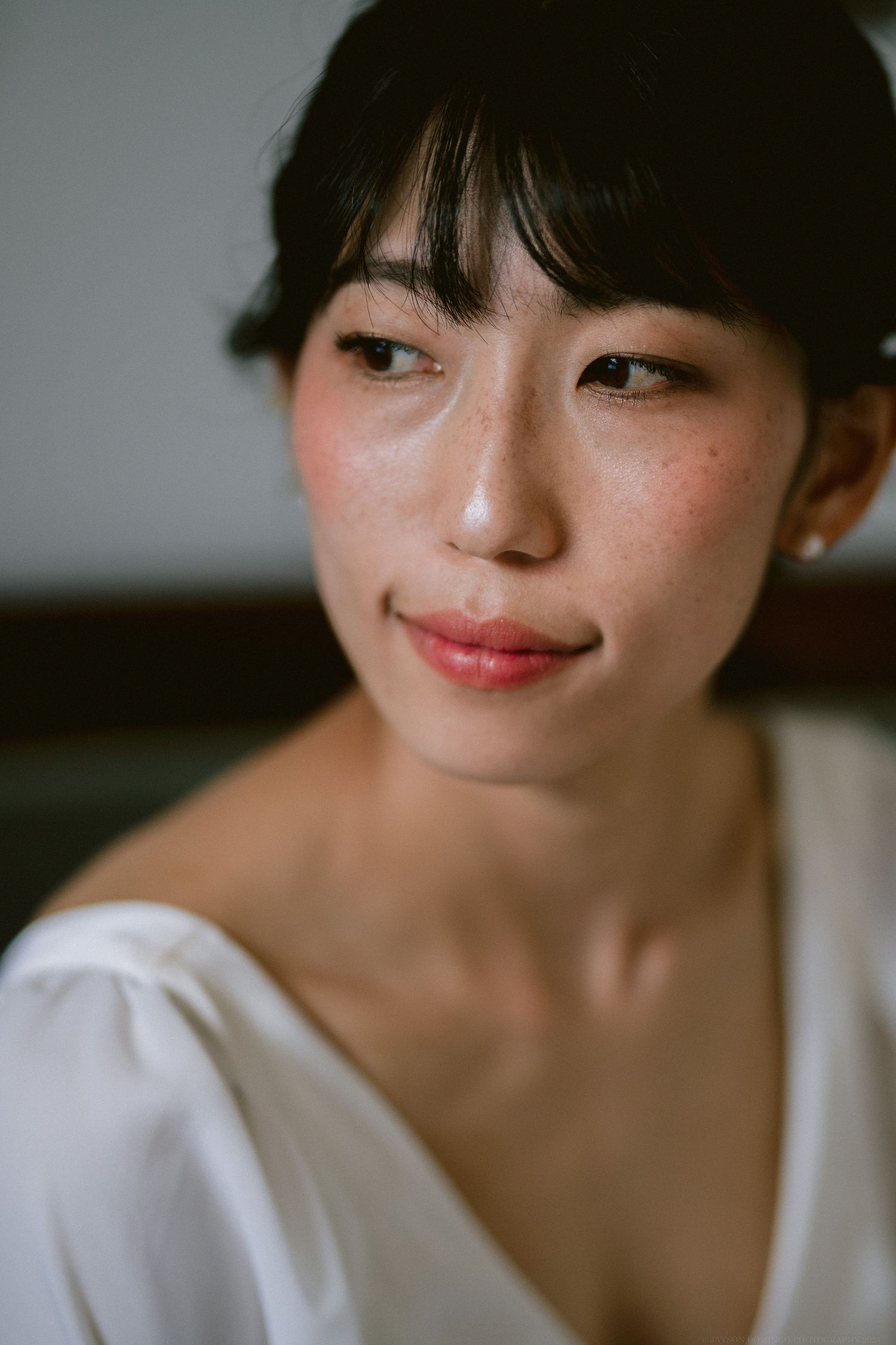 Close-up beauty portrait showing natural makeup and white dress detail.