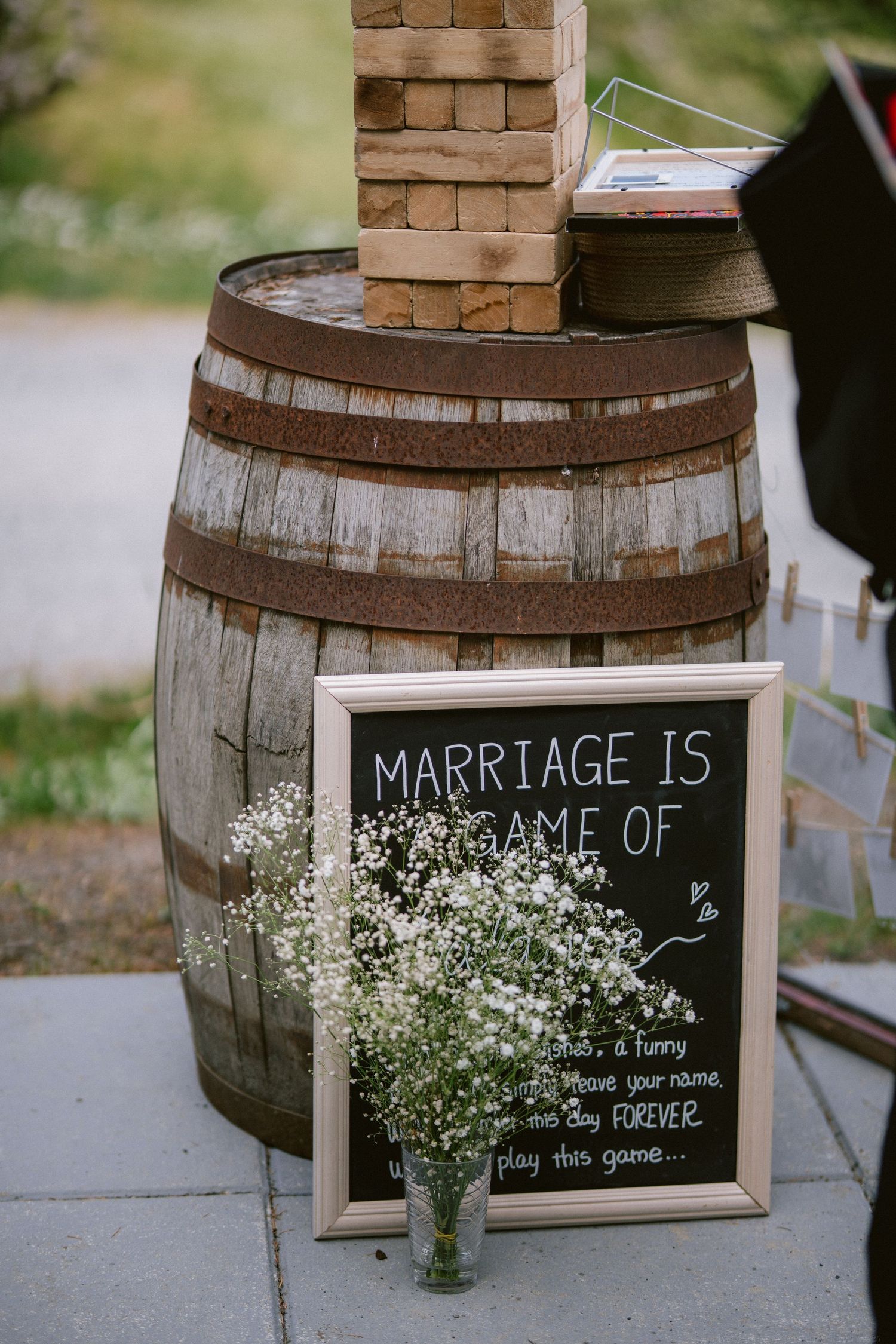 A rustic wine barrel with a chalkboard sign about marriage and small white flowers in a wedding decor setting.