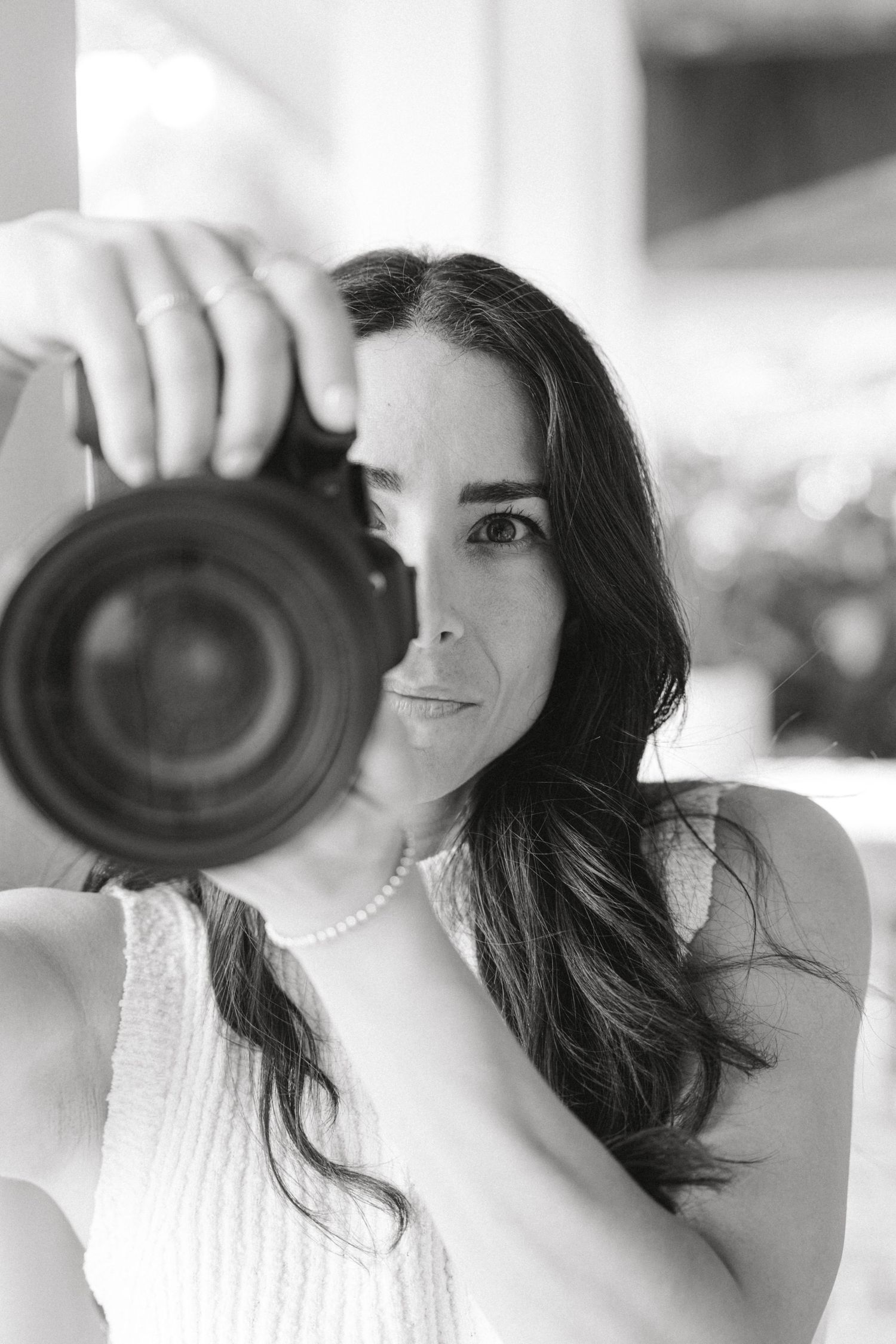 Black and white portrait series of a photographer holding a camera lens in multiple poses.