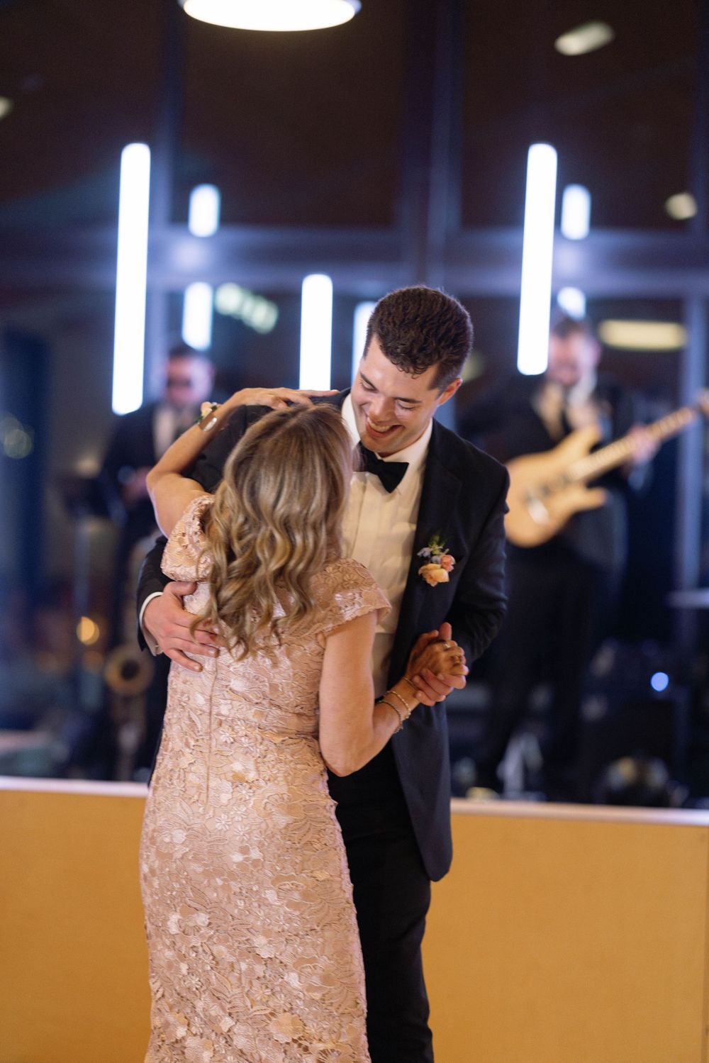 A couple dancing at a wedding reception with the bride wearing a blush sequined gown and groom in classic tuxedo.