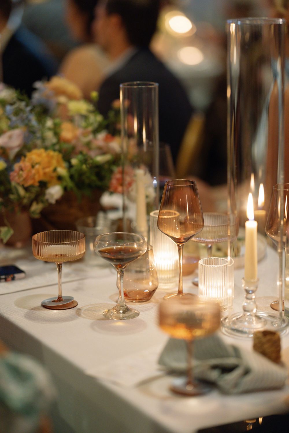 Elegant table setting with wine glasses, candlelight and floral arrangements at a romantic evening event.