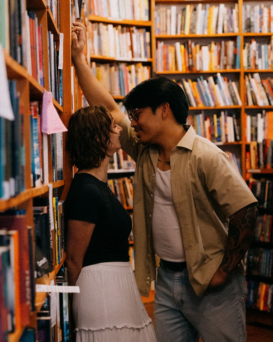 A couple having a cute intimate moment in a bookstore.