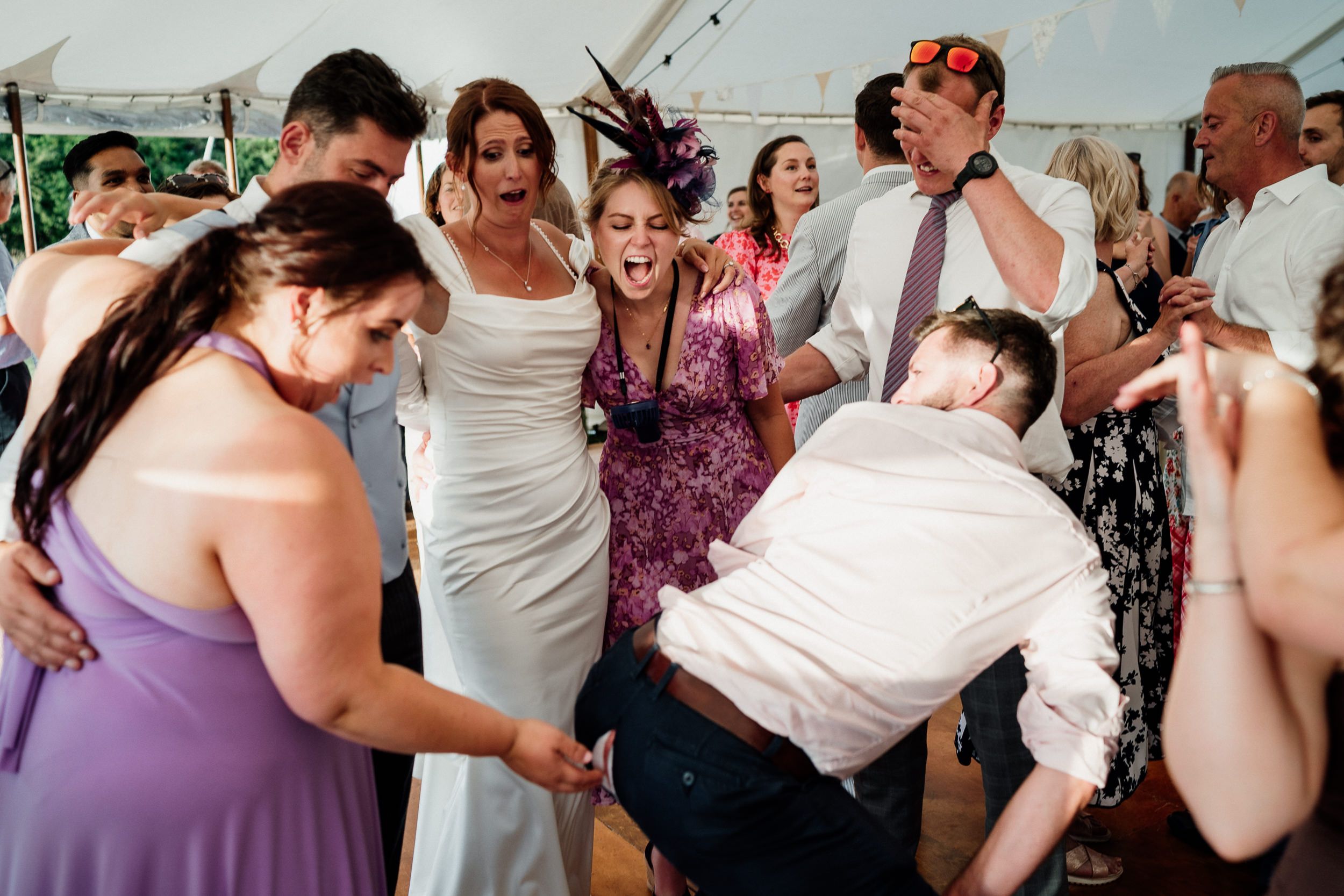 Wedding reception guests dance and celebrate together on a lively dancefloor with confetti in the air.