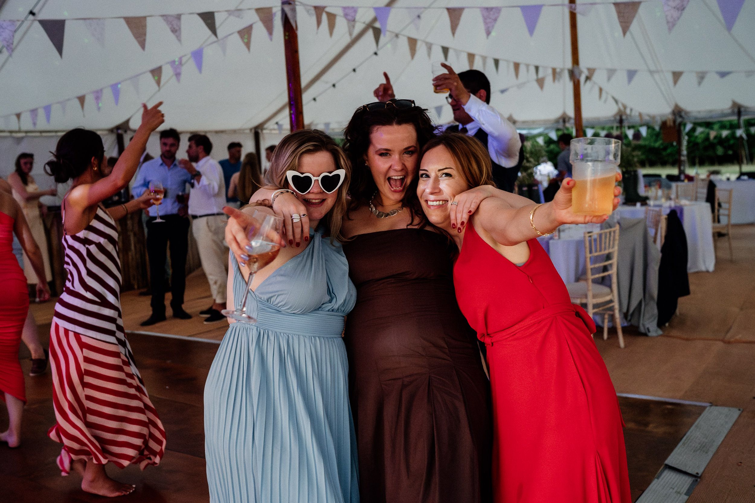 People dancing and celebrating at a wedding reception under colorful bunting flags.
