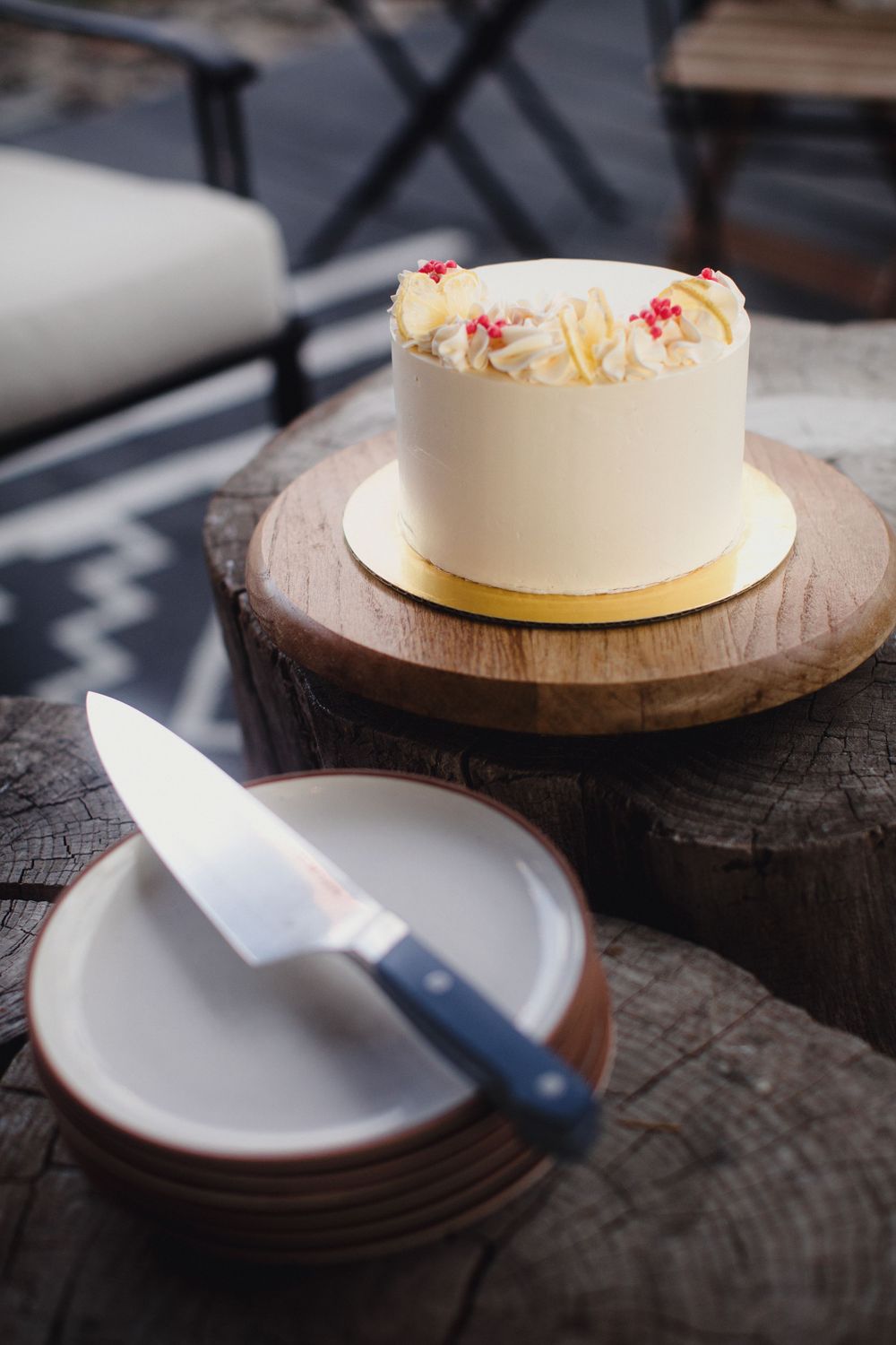 Step by step sequence showing the process of placing a white frosted cake on a rustic wooden serving board.