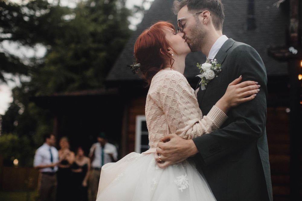 A romantic wedding moment captured outdoors with the newlyweds embracing in their elegant white gown and dark suit.