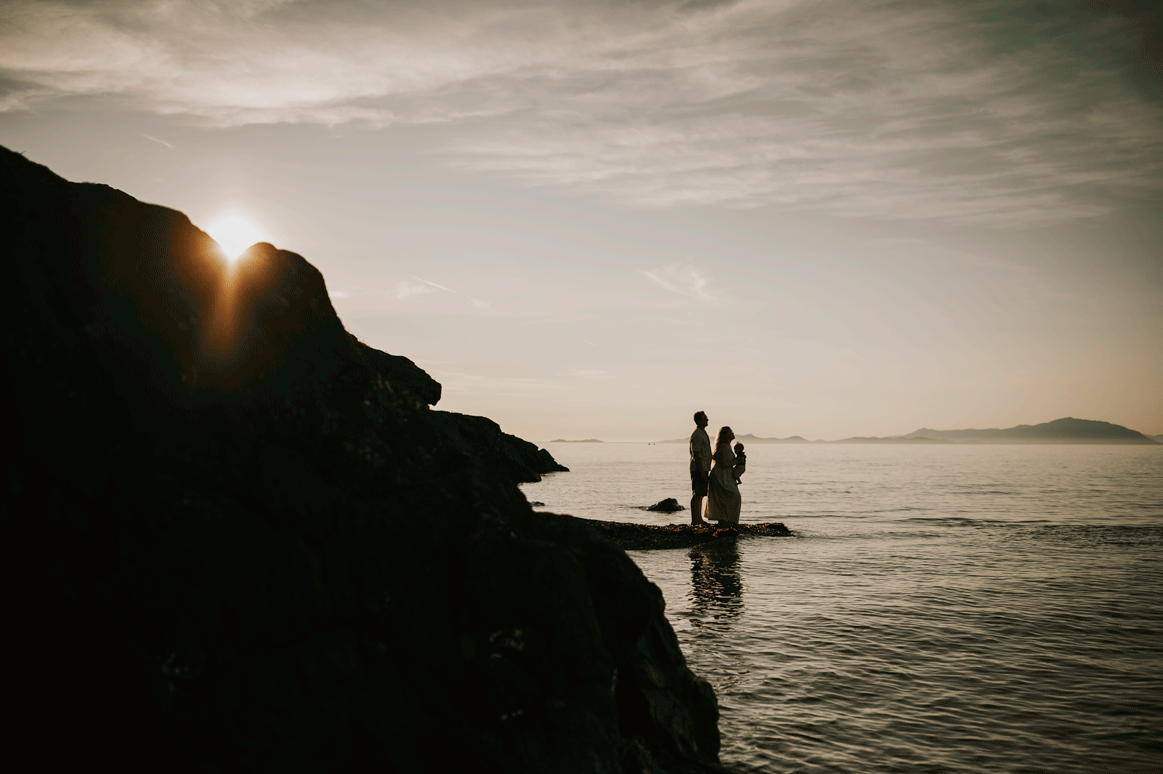 Candid gif of family holding baby in air by rocky ocean Neck Point Park Nanaimo sunset family photography by Vancouver Island photographer